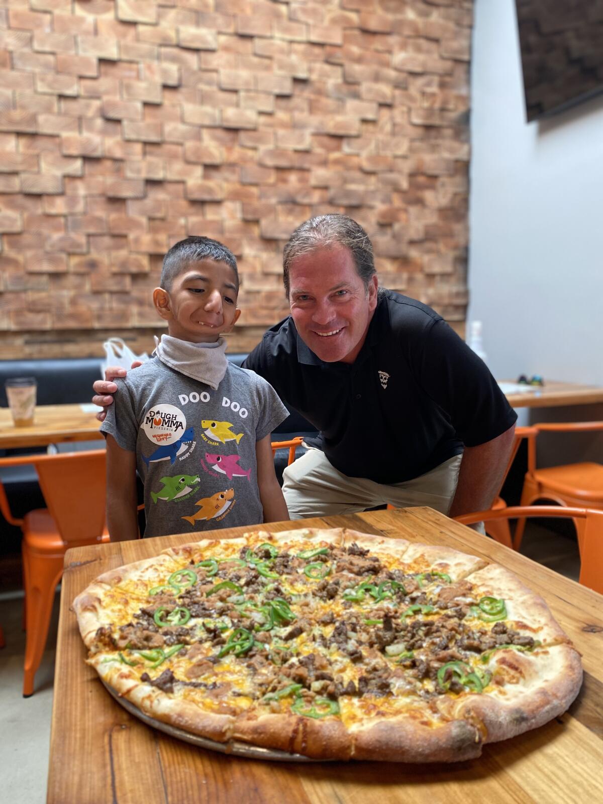 Dani Trejo, 7, and Dough Momma Pizzeria owner Darren Moore show Dani's winning pizza.