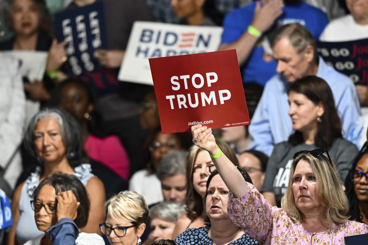 A woman holds a sign that reads "Stop Trump" at a Biden campaign rally 