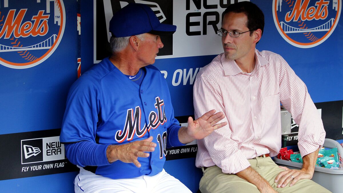 Mets Manager Terry Collins talks with Paul DePodesta, the team's president of player development and amateur scouting, before a game.