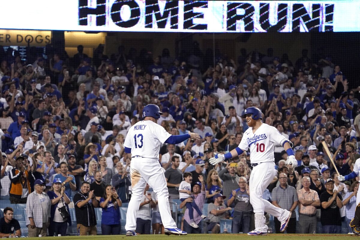 Los Angeles Dodgers' Justin Turner, right, is congratulated by Max Muncy as he scores after hitting a two-run home run during the seventh inning of a baseball game against the San Diego Padres Thursday, June 30, 2022, in Los Angeles. (AP Photo/Mark J. Terrill)