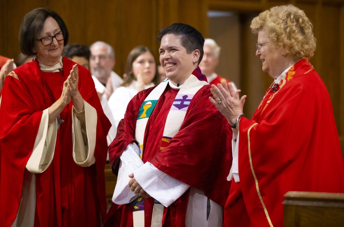 Pacyniak, center, is applauded by Bishop Jane Via, left, and Bishop Suzanne Avison Thiel, right, during the ordination ceremony.