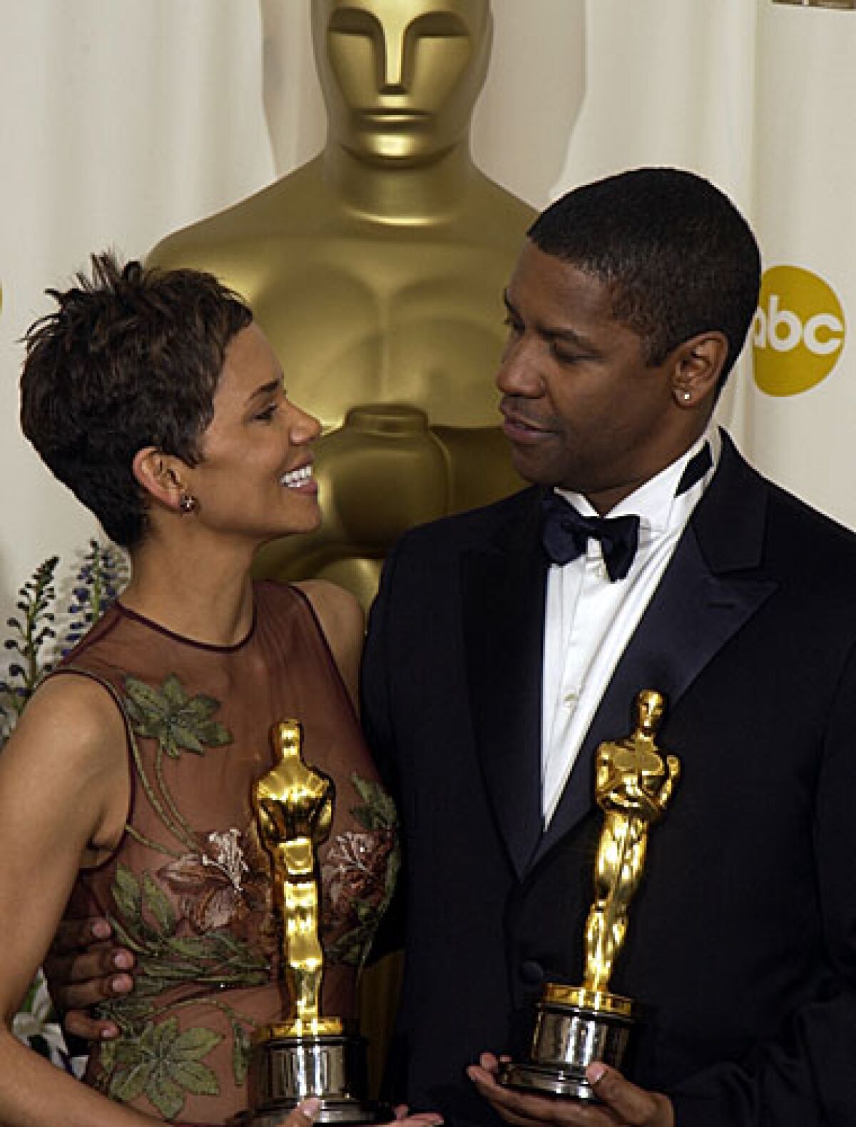 Halle Berry and Denzel Washington each hold an Oscar statuette, 20 years ago.
