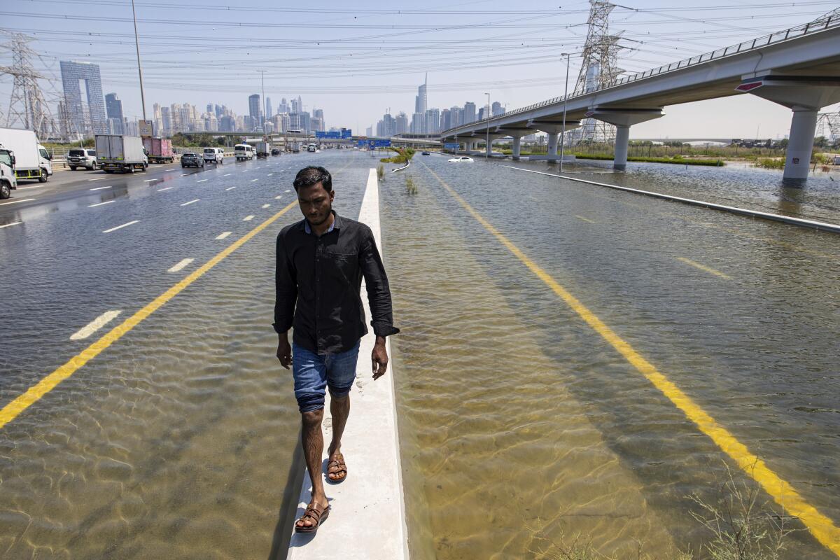 A man walks along a road barrier to avoid floodwater.
