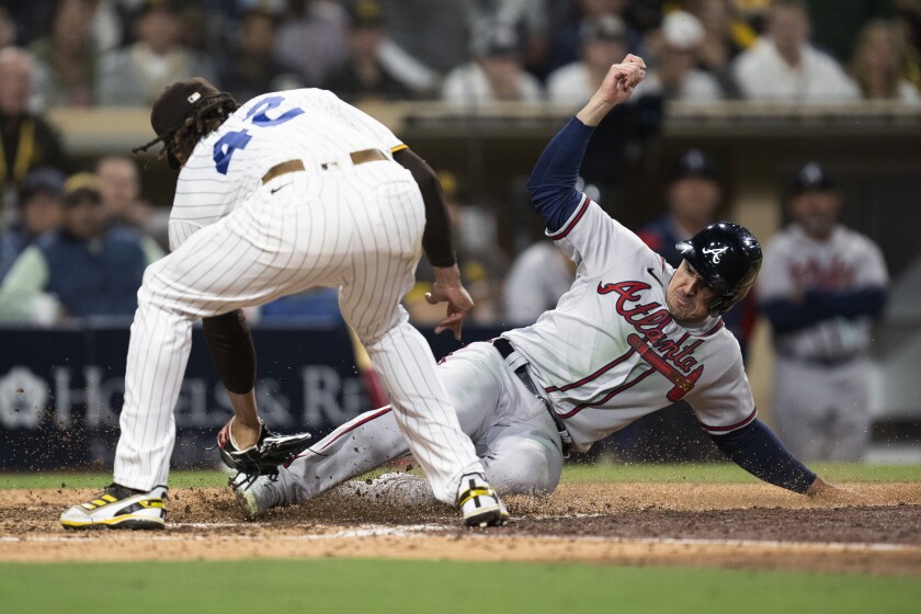 Adam Duvall scores of the Atlanta Braves (right) closing the bunt of San Diego Padres reliever Dinelson Lamette on a wooded pitch in the eighth inning of an MLB game between the two teams on April 15, 2022 in San Diego.  (AP Photo / Kyusung Gong)
