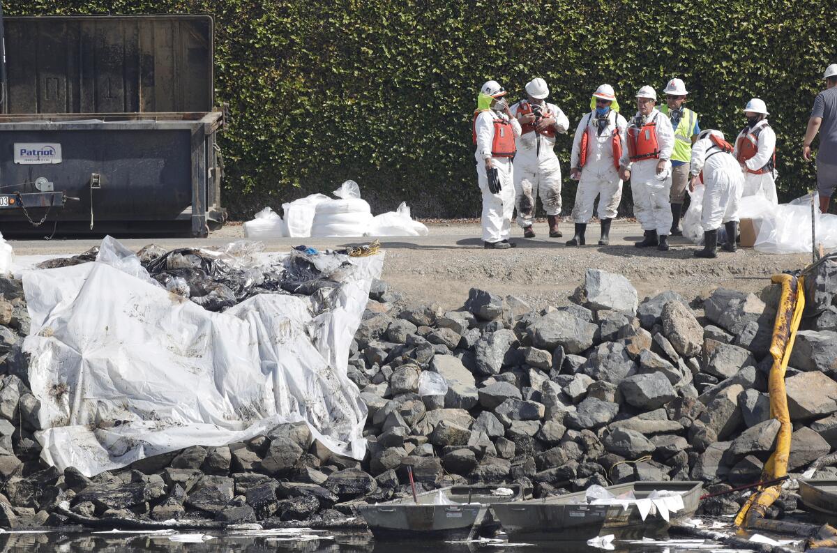 A cleanup crew pause after they filled and hauled bags of crude oil out of Talbert Marsh on Oct. 4.