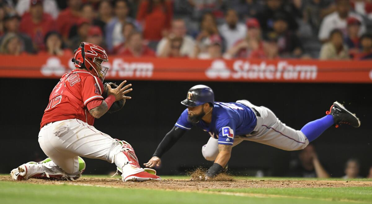 Rougned Odor of the Texas Rangers dives to the plate beating the throw to Martin Maldonado in the 10th inning for the winning run.