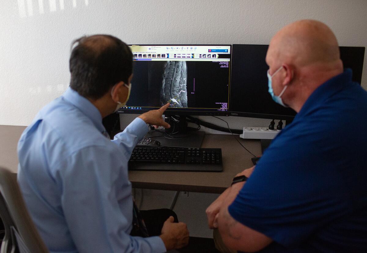 a doctor and patient review an MRI on a computer screen