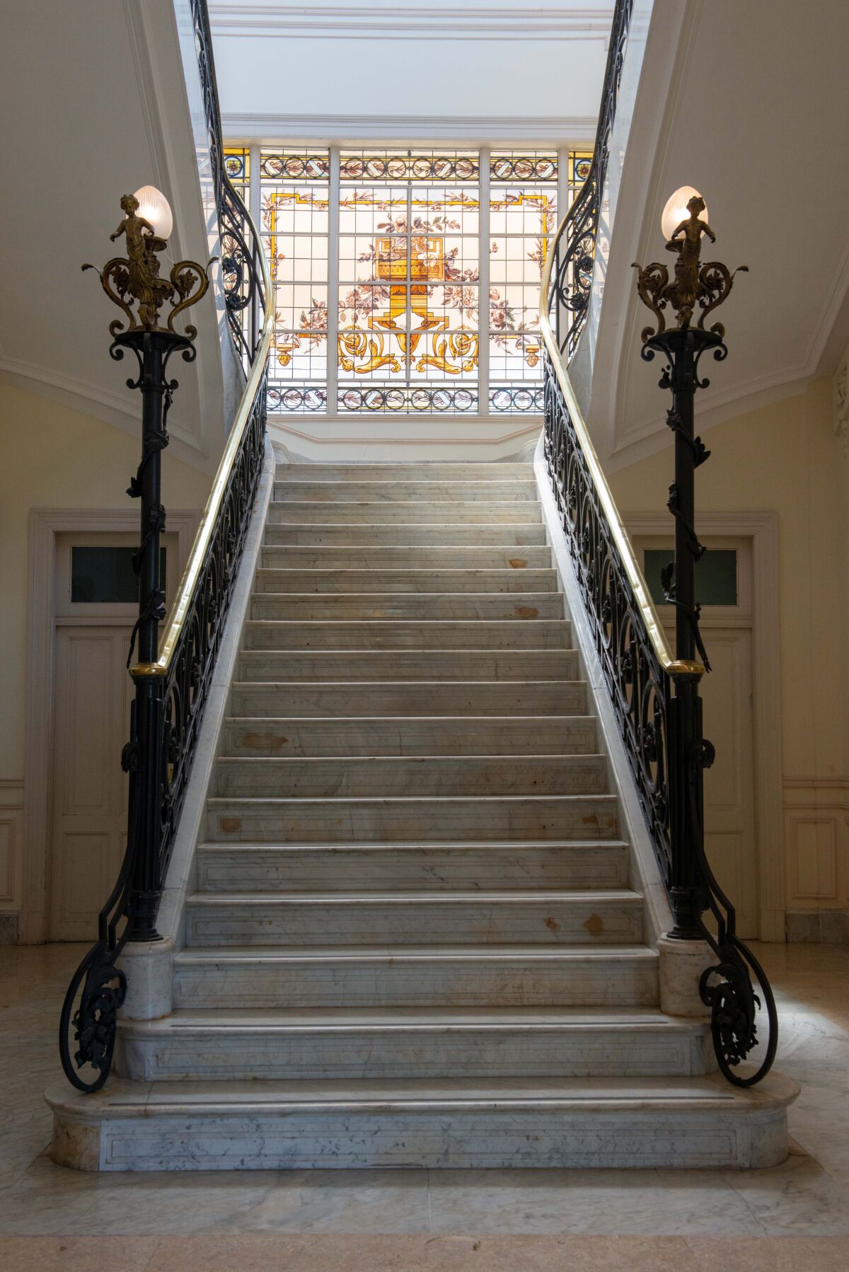 The Tigre Art Museum's long Carrara marble staircase is seen with a stained-glass window at the top.