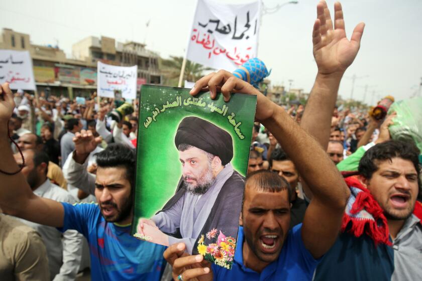 A supporter of Muqtada Sadr holds a portrait of the Shiite cleric during a protest against corruption in Baghdad's Sadr City neighborhood on May 6, 2016.