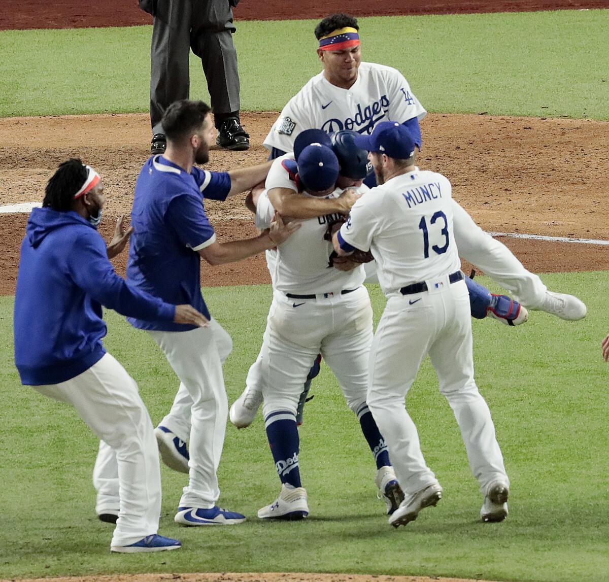 Pitcher Julio Urías is at the center of leaping, hugging players.
