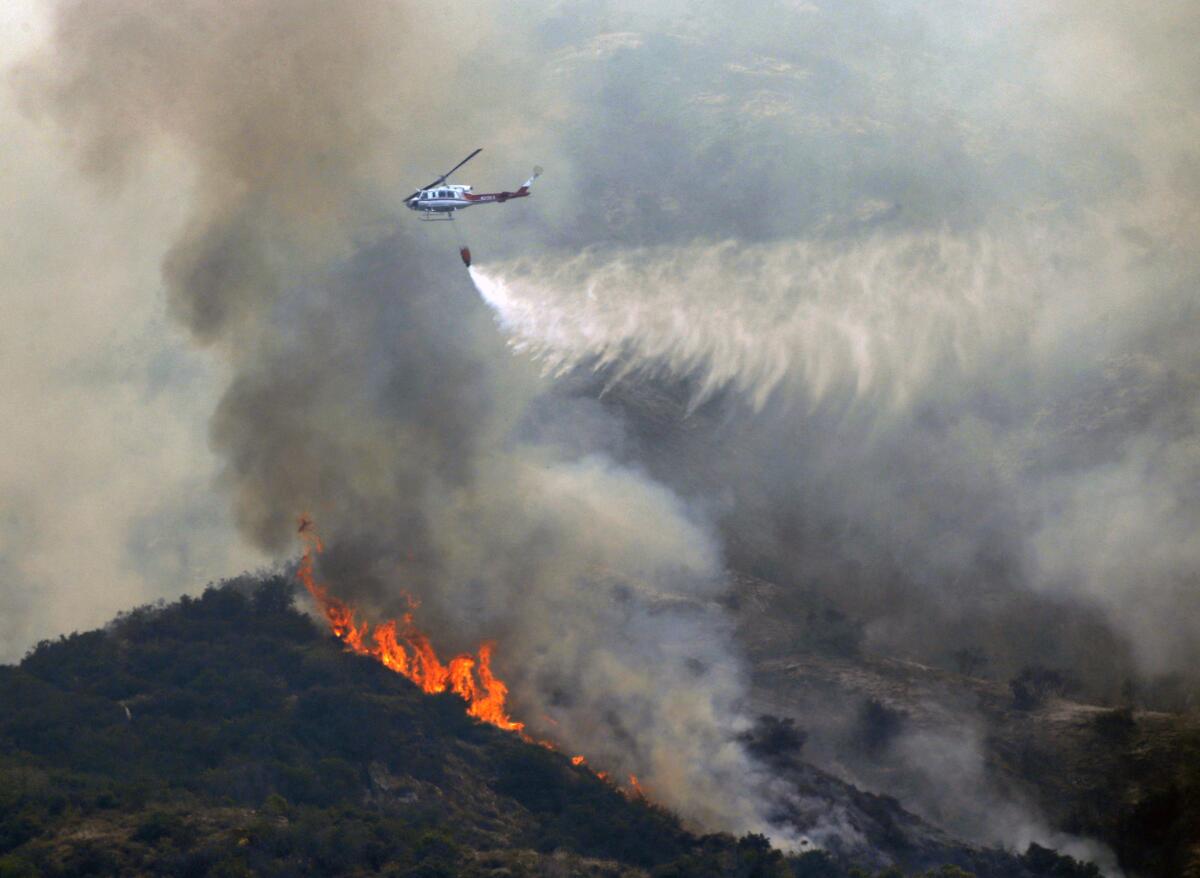 Un helicóptero contra incendios tira agua sobre maleza en llamas cerca de Bradbury, California, el miércoles 22 de junio del 2016. (Foto AP /Nick Ut)