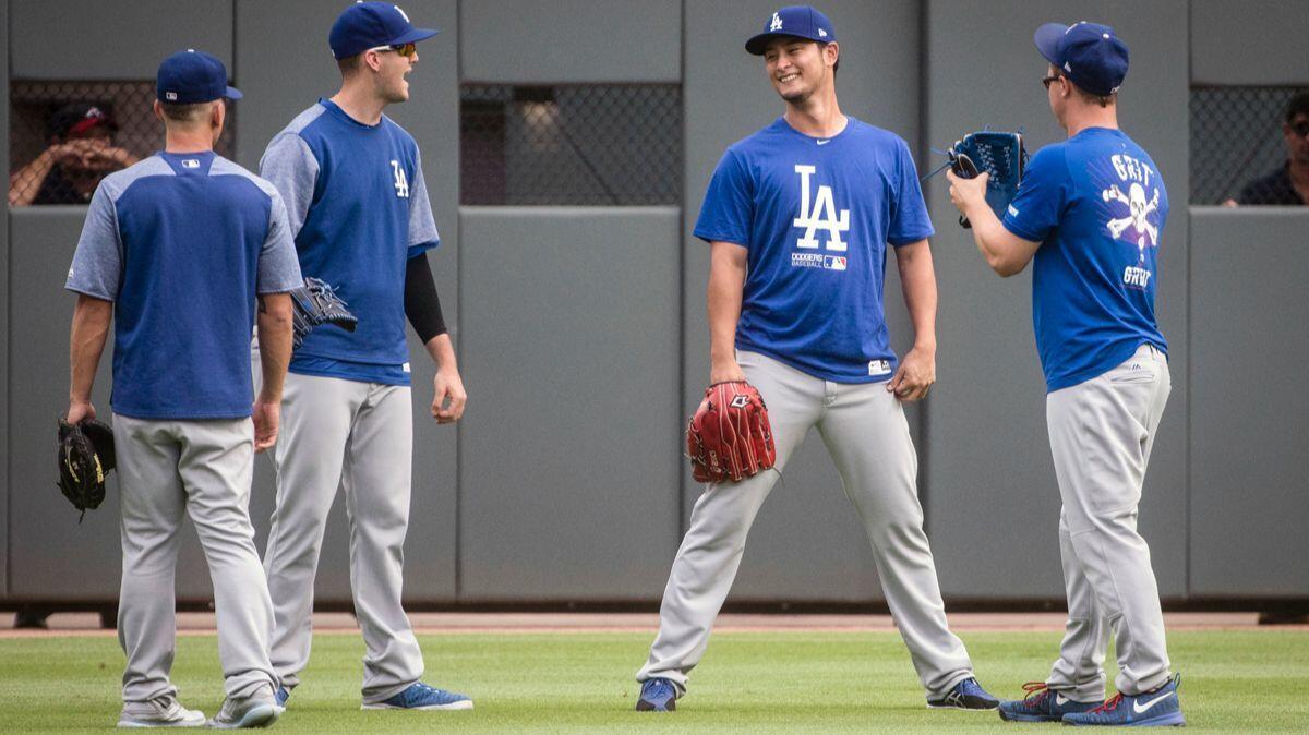 Dodgers' Yu Darvish, second from right, Austin Barnes, left, Alex Wood and Joc Pederson, right, talk in the outfield as the Dodgers warm up before a game against the Atlanta Braves on Wednesday.