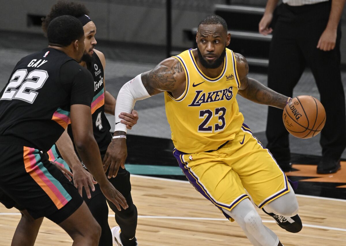 Lakers star LeBron James drives against San Antonio Spurs' Rudy Gay and Derrick White.