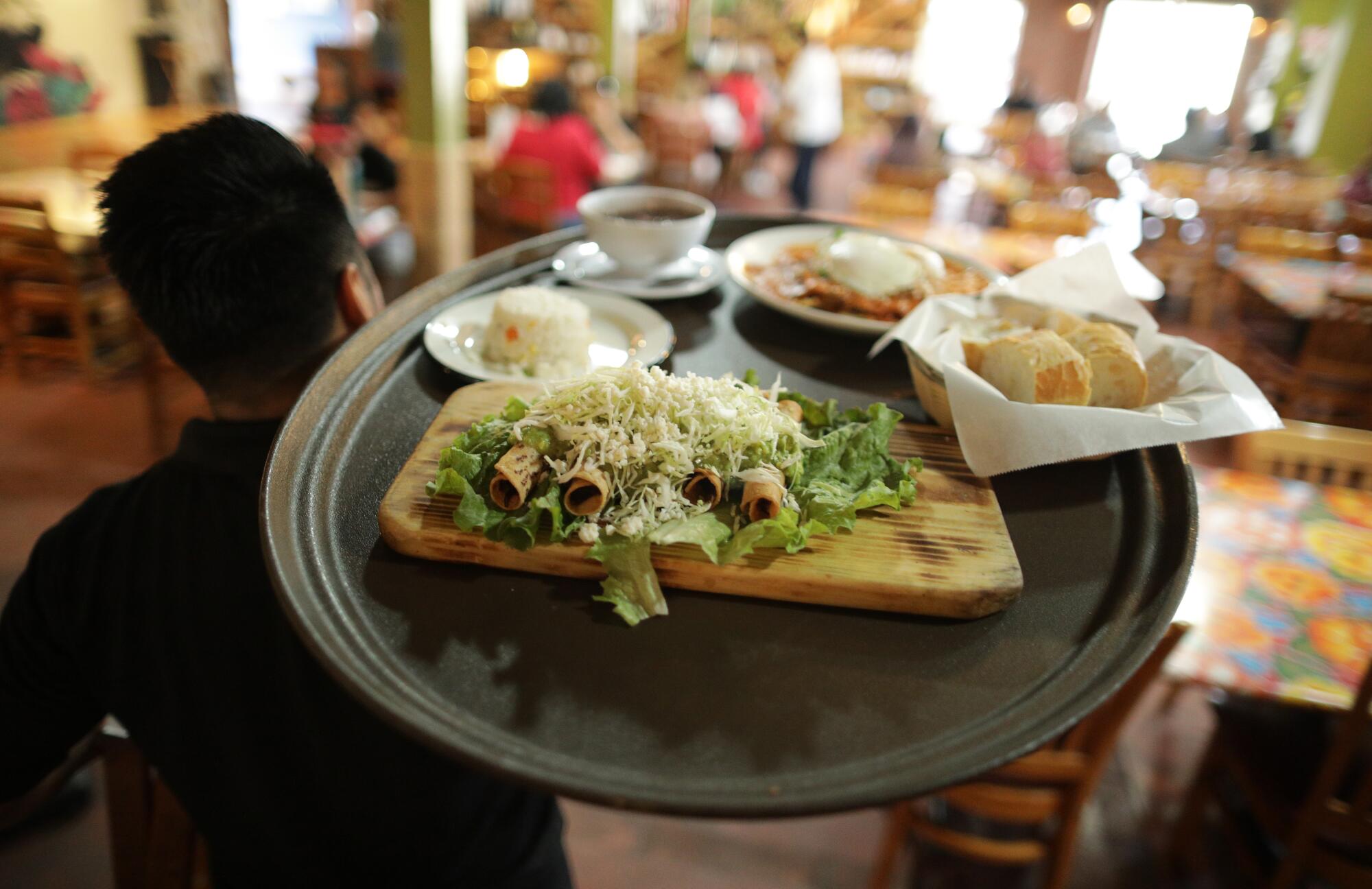 An overhead view of food on a waiter's tray as he walks away from the camera.