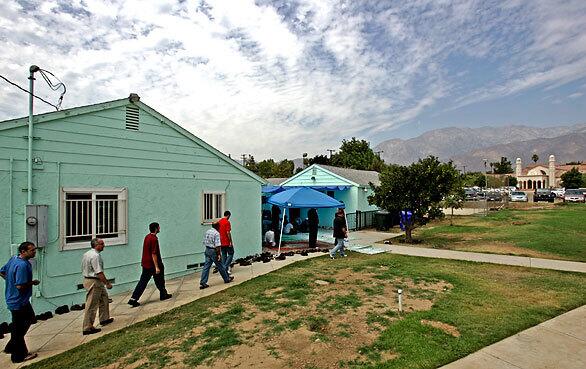On a hot day, members of the Islamic Center of Inland Empire in Rancho Cucamonga head for what they hoped would be their last Friday prayers at an old stucco house, which has served as their mosque since 2000, before their newly built mosque opens. The new mosque is visible at right rear.