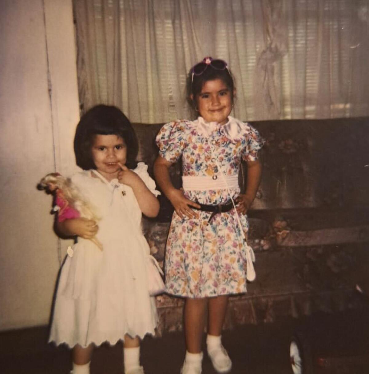 Photo of two young girls, one is holding a barbie doll 