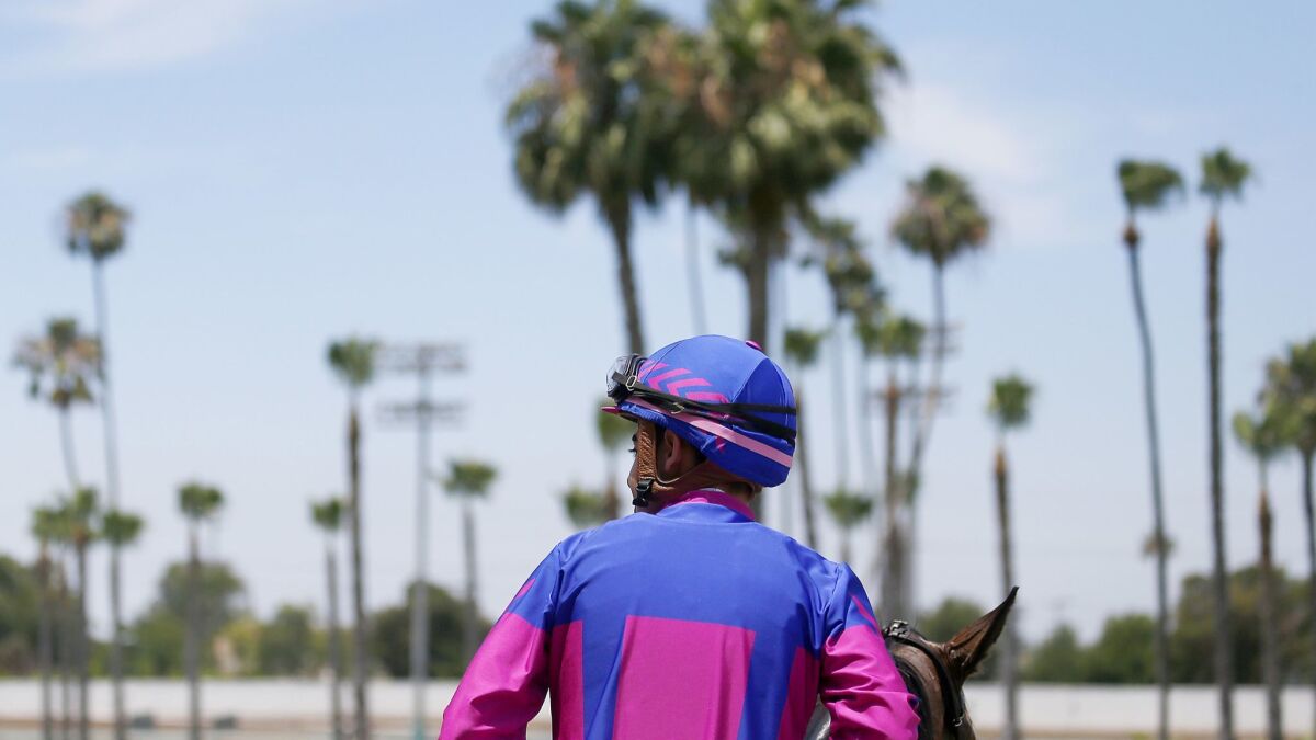 A jockey cools down his horse after a race at the Los Alamitos Race Course in June 2019.