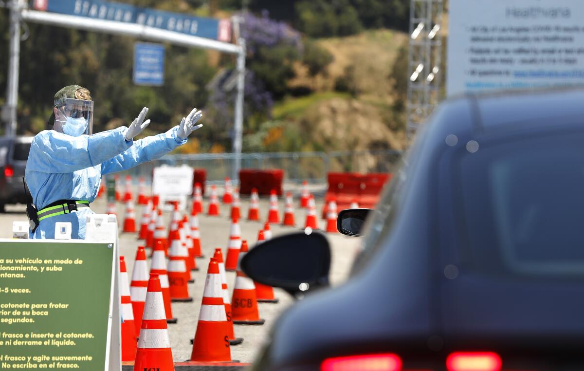 Worker directs traffic at drive-through coronavirus testing site at Dodger Stadium