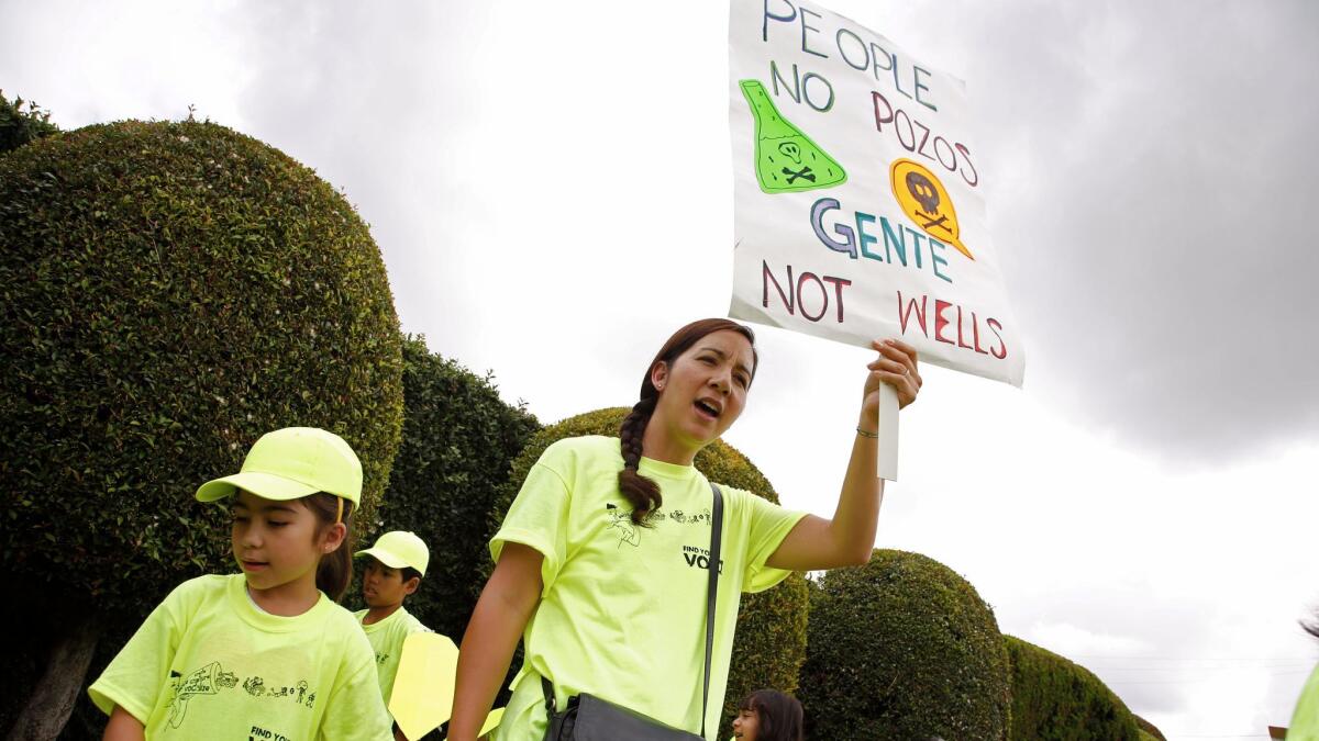 Lisa Placenti and her daughter Isabella, 7, participate in a protest in front of a drilling site at Jefferson Boulevard and Budlong Avenue in South Los Angeles.