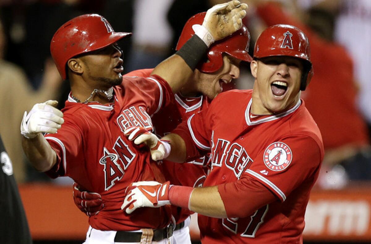 Angels teammates Luis Jimenez, left, Josh Hamilton, center, and Mike Trout celebrate after Albert Pujols drove in Jimenez and Trout to defeat the Houston Astros on Saturday night in Anaheim.