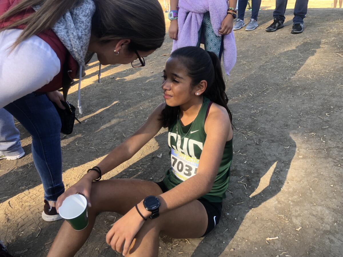 Sophomore Sofia Abrego of Granada Hills receives support from a family friend after winning her second consecutive City Section Division I girls' cross-country championship.