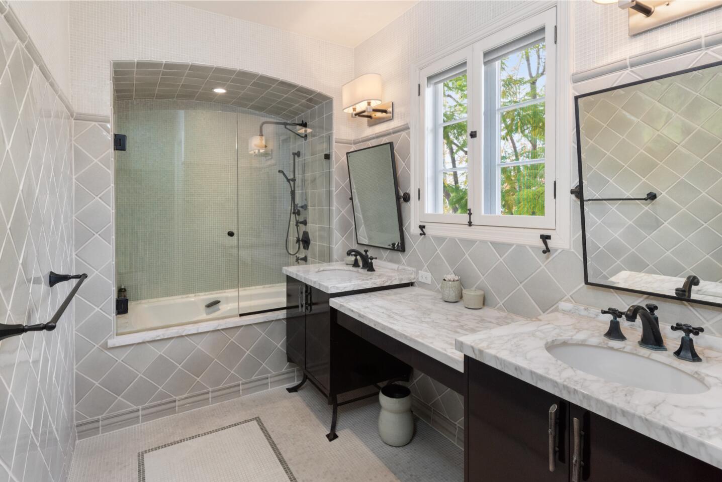 A dark-wood vanity, gray tile and shower-tub combination.