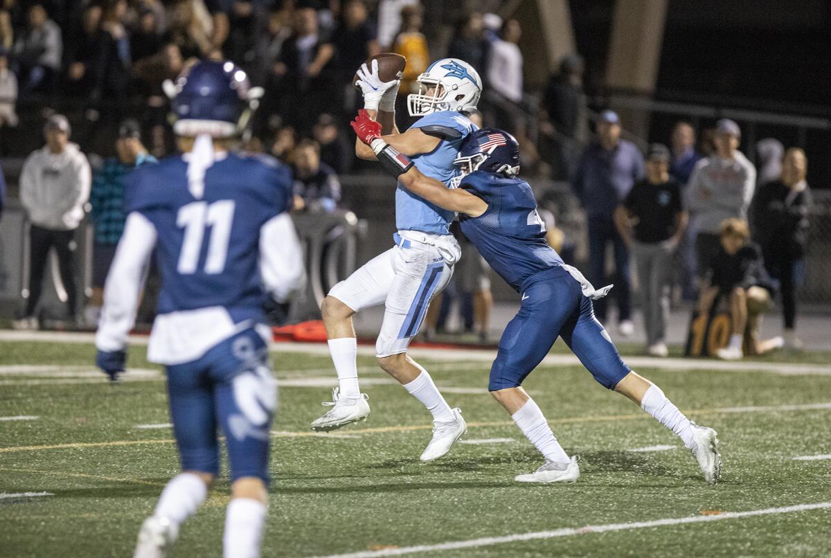 Corona del Mar's Max Lane catches a pass under pressure from Newport Harbor's Carson de Avila on Oct. 22.