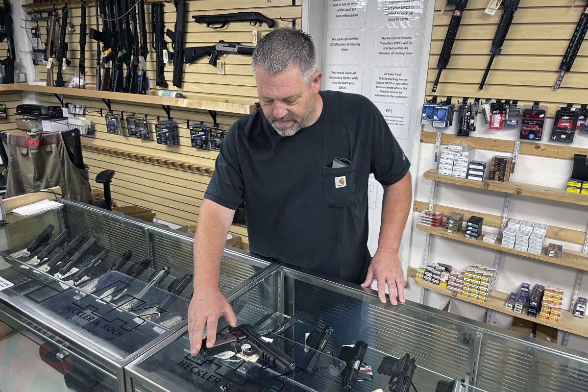 John Parkin displays a handgun at his store in Burlingame in June 2022. 