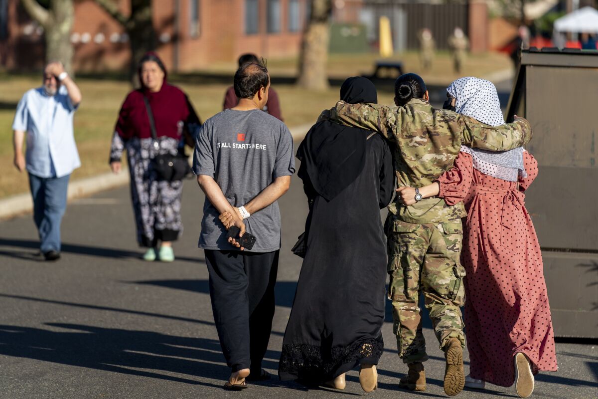 A member of the military puts her arms around two female Afghan refugees at a refugee camp on Sept. 21 in Lakehurst, N.J.