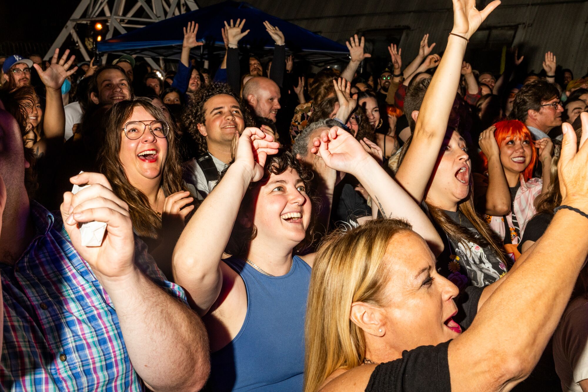 A crowd of people with excited facial expressions watch a performance.