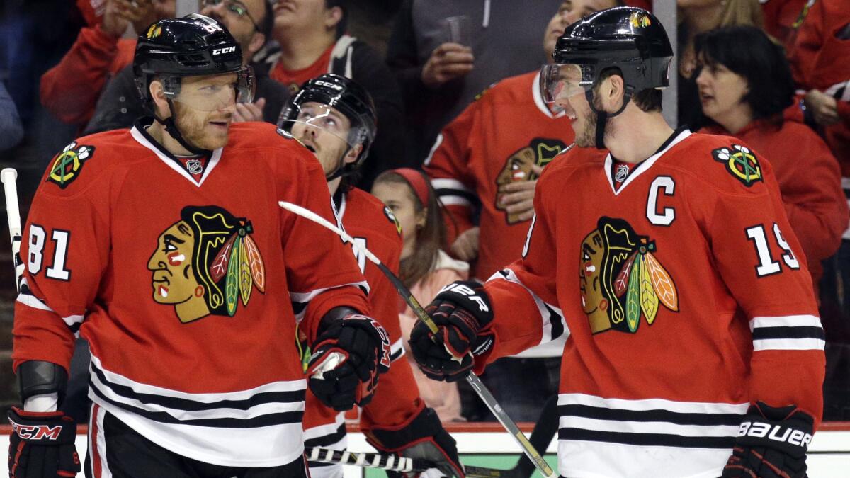 Chicago Blackhawks captain Jonathan Toews, right, smiles as he celebrates with teammate Marian Hossa (81) after scoring a first-period goal during the team's 4-1 win over the Minnesota Wild in Game 2 of the Western Conference semifinals Sunday.