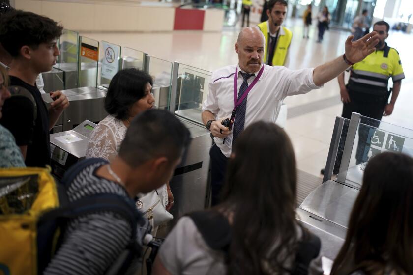 Employees try to give directions to passengers crowded at the entrance to the platforms, at Sants train station in Barcelona, Sunday, May 12, 2024. Catalonia's commuter rail service said it was forced to shut down several train lines due to the robbery of copper cables from an installation near Barcelona. Potentially thousands of voters had trouble reaching their polling stations after Catalonia's commuter rail service had to shut down several train lines due to what officials said was the robbery of copper cables from an installation near Barcelona. (AP Photo/Joan Mateu Parra)