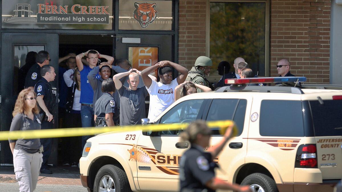 Students put their hands on their heads as they are led out of Fern Creek Traditional High School in Louisville, Ky.
