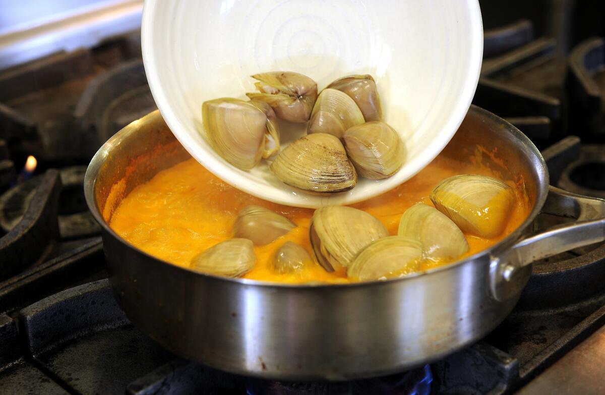 Chef Louis Tikaram adds a handful of clams to the curry. As he stirs, the sauce turns the color of a deep orange sherbet.