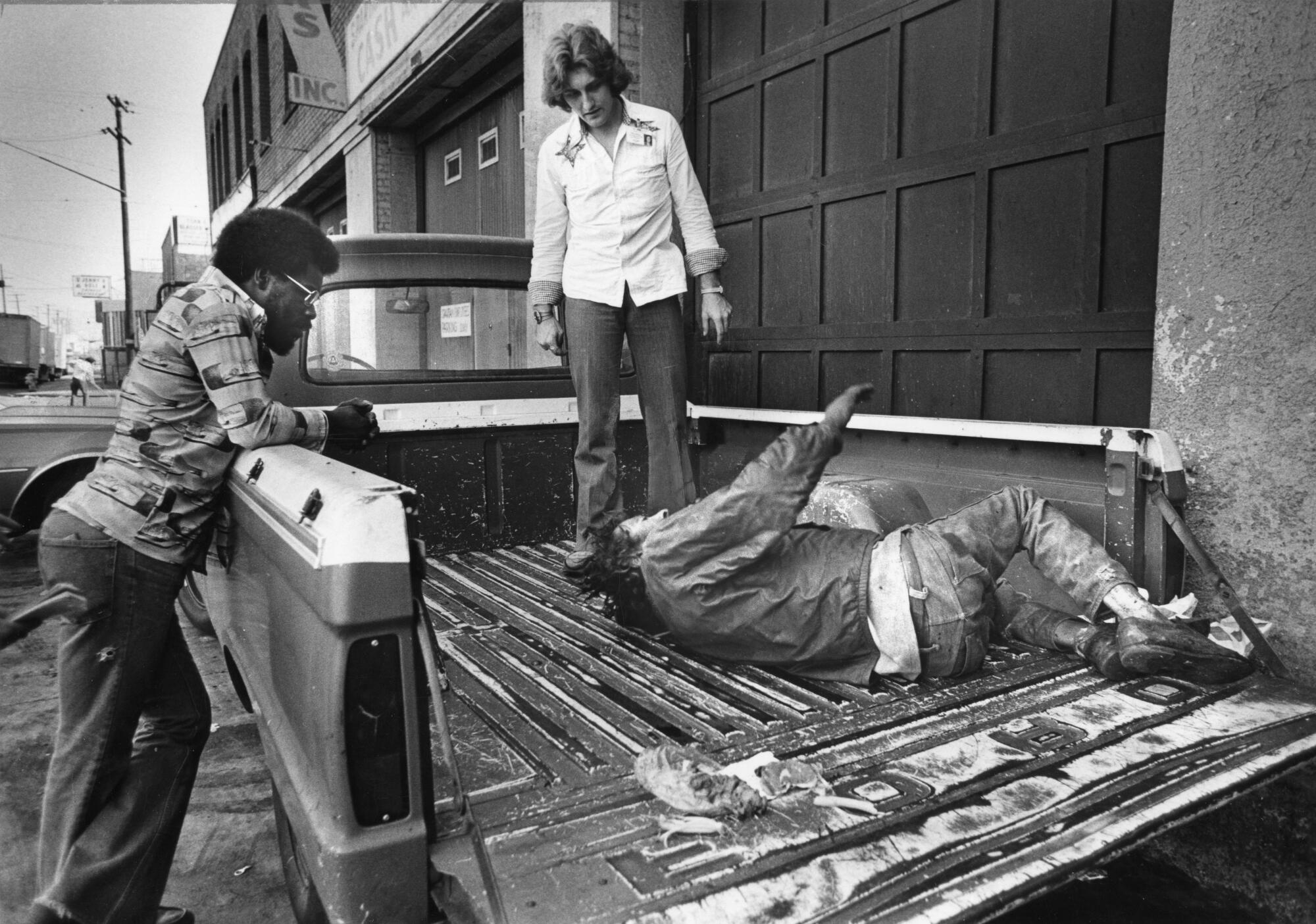 Members of the Public Inebriation Program's Civilian Assistance Patrol help a man in the bed of a pickup truck.