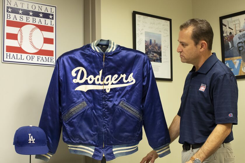 Josh Rawitch looks at a jacket and cap belonging to Dodgers legend Duke Snider.