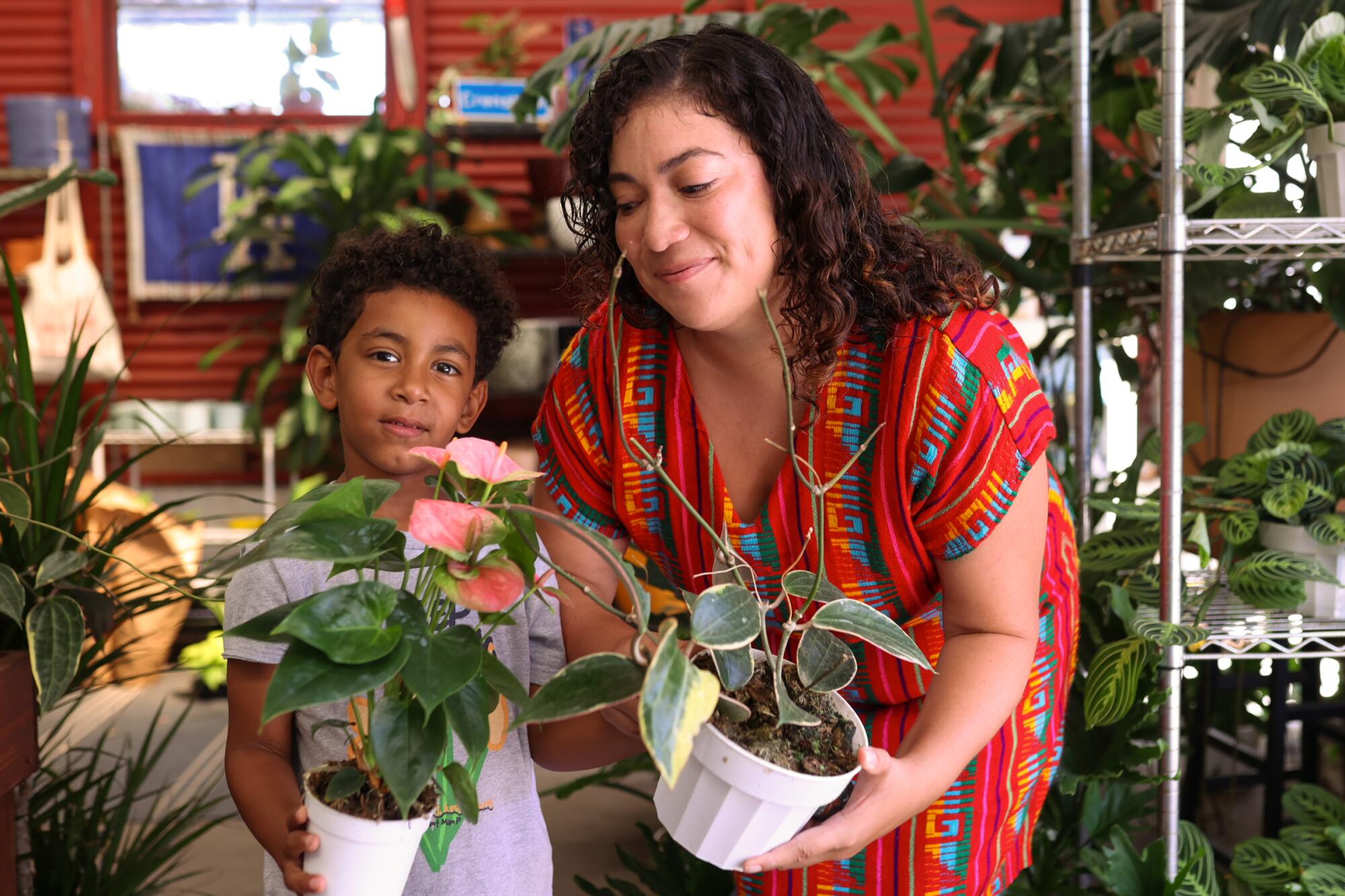 A young boy and his mom hold potted plants inside Plant Chica, an auto shop turned plant shop.