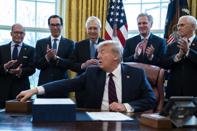 President Donald Trump reaches for a pen during a ceremony to sign the coronavirus stimulus relief package in the Oval Office at the White House, Friday, March 27, 2020, in Washington. From left, White House chief economic adviser Larry Kudlow, Treasury Secretary Steven Mnuchin, Senate Majority Leader Mitch McConnell of Ky., Trump, House Minority Leader Kevin McCarty, R-Calif., and Vice President Mike Pence. (AP Photo/Evan Vucci)