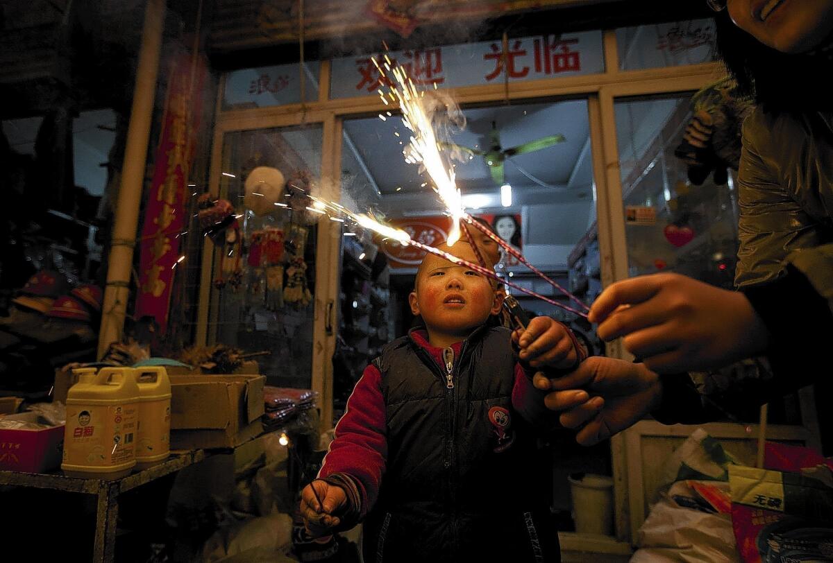 A woman lights sparklers for her child outside a market in Shanxian in China's Shandong province. Fireworks are an integral part of Chinese New Year.