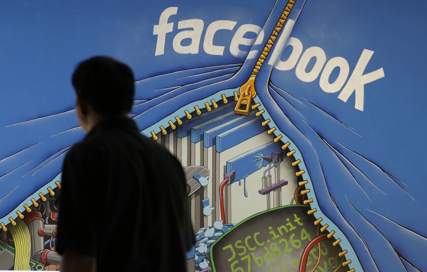 A man walks past a mural in an office on the Facebook campus in Menlo Park, Calif.