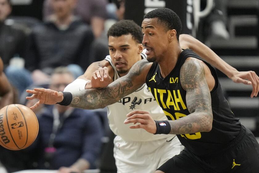 San Antonio Spurs center Victor Wembanyama, left, and Utah Jazz forward John Collins reach for ball during the first half of an NBA basketball game Wednesday, March 27, 2024, in Salt Lake City. (AP Photo/Rick Bowmer)