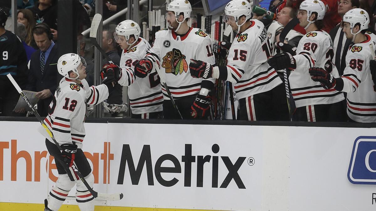 Chicago Blackhawks left wing Alex DeBrincat (12) is congratulated by teammates after scoring a goal against the San Jose Sharks during the first period on Thursday.