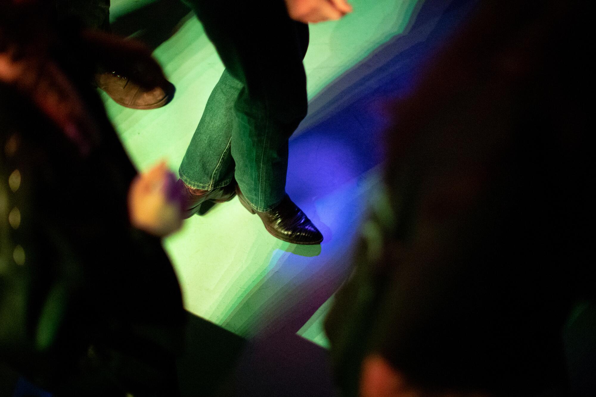 The pointed toes of cowboy boots peek out from between lines of dancers.