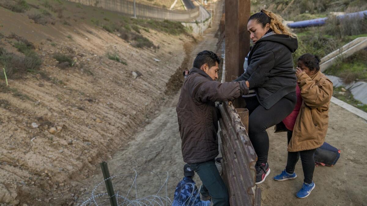 A pregnant migrant climbs the border fence before jumping into the U.S. to San Diego from Tijuana, Mexico, on Dec. 27.