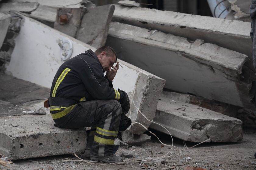 A rescue worker takes a pause as he sits on the debris at the scene where a woman was found dead after a Russian attack that heavily damaged a school in Mykolaivka, Ukraine, Wednesday, Sept. 28, 2022. (AP Photo/Leo Correa)