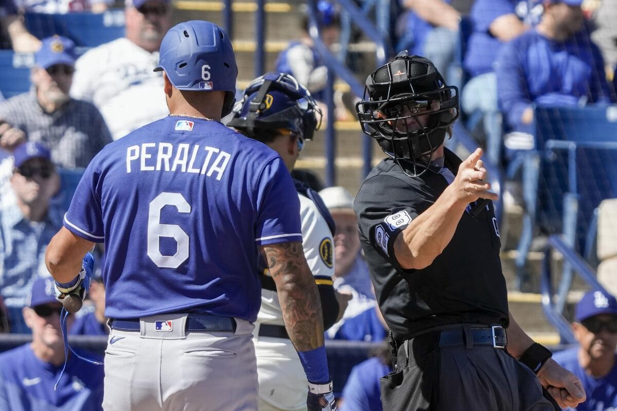 Home plate umpire Jim Wolf tells Dodgers batter David Peralta to take first base after a pitching clock violation.