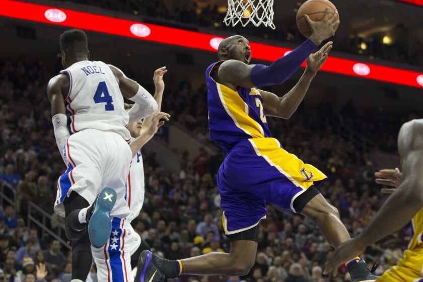 Lakers forward Kobe Bryant goes by a leaping Nerlens Noel and makes a reverse layup.