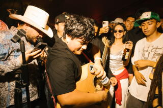 A guitarist plays his guitar with a beer