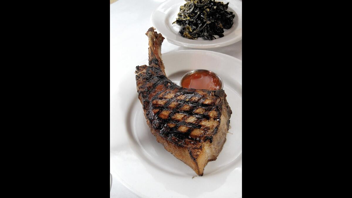 The pork rib chop with braised greens at Salt's Cure in West Hollywood.