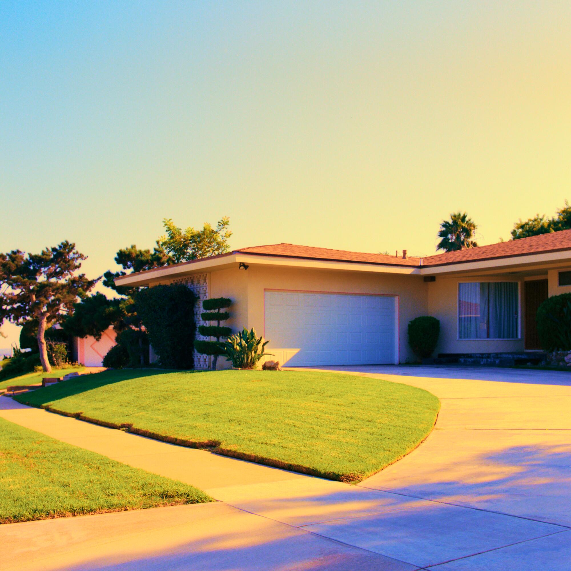 A photo of a curving driveway in front of a beige house.